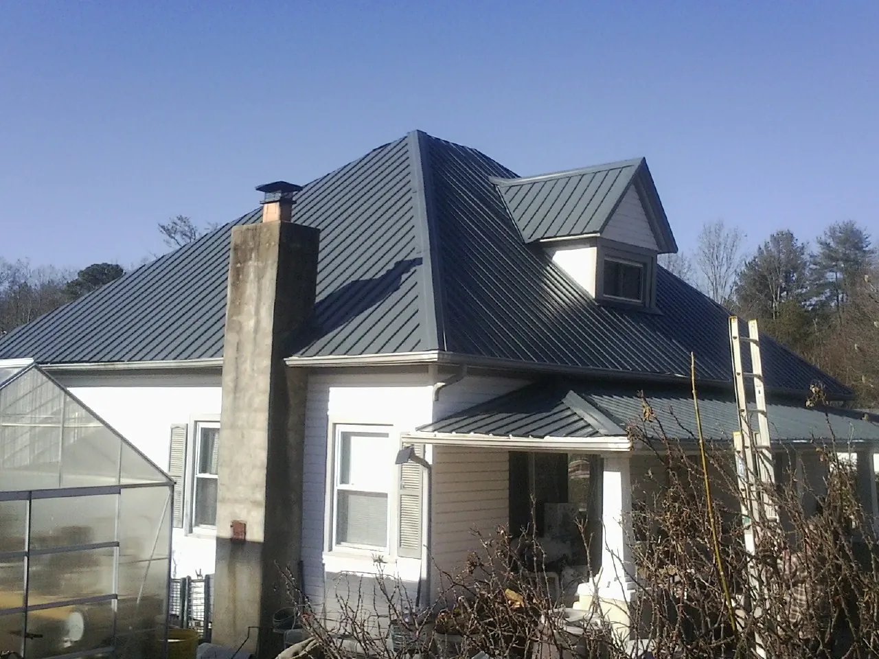 Dark blue standing seam metal roof on a white farmhouse with dormer — Slate & Tile Roof Repair by Roofing Brothers in Five Points