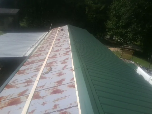 Old rusted panels beside newly installed green metal roofing — Wind Damage Roof Repair by Roofing Brothers in Five Points