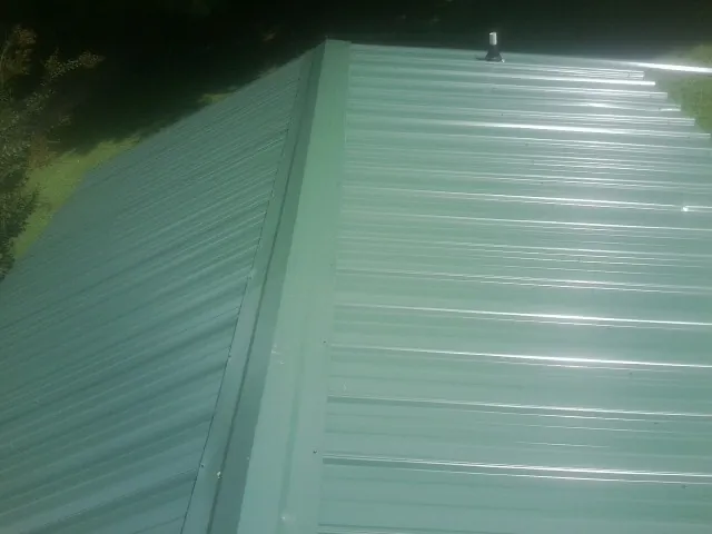 New green metal panels meeting at the ridge of a roof — Flat Roof Repair work by our crew in Five Points