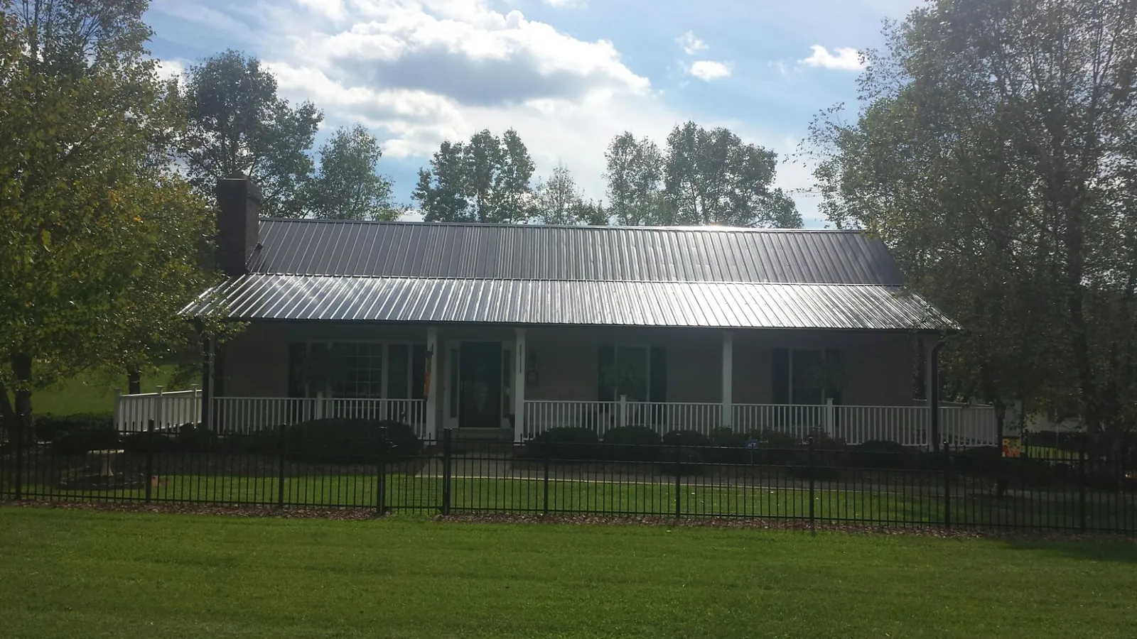 Gray metal roof on a brick ranch with a full width front porch — Gutter Guard Installation work by our crew in Five Points
