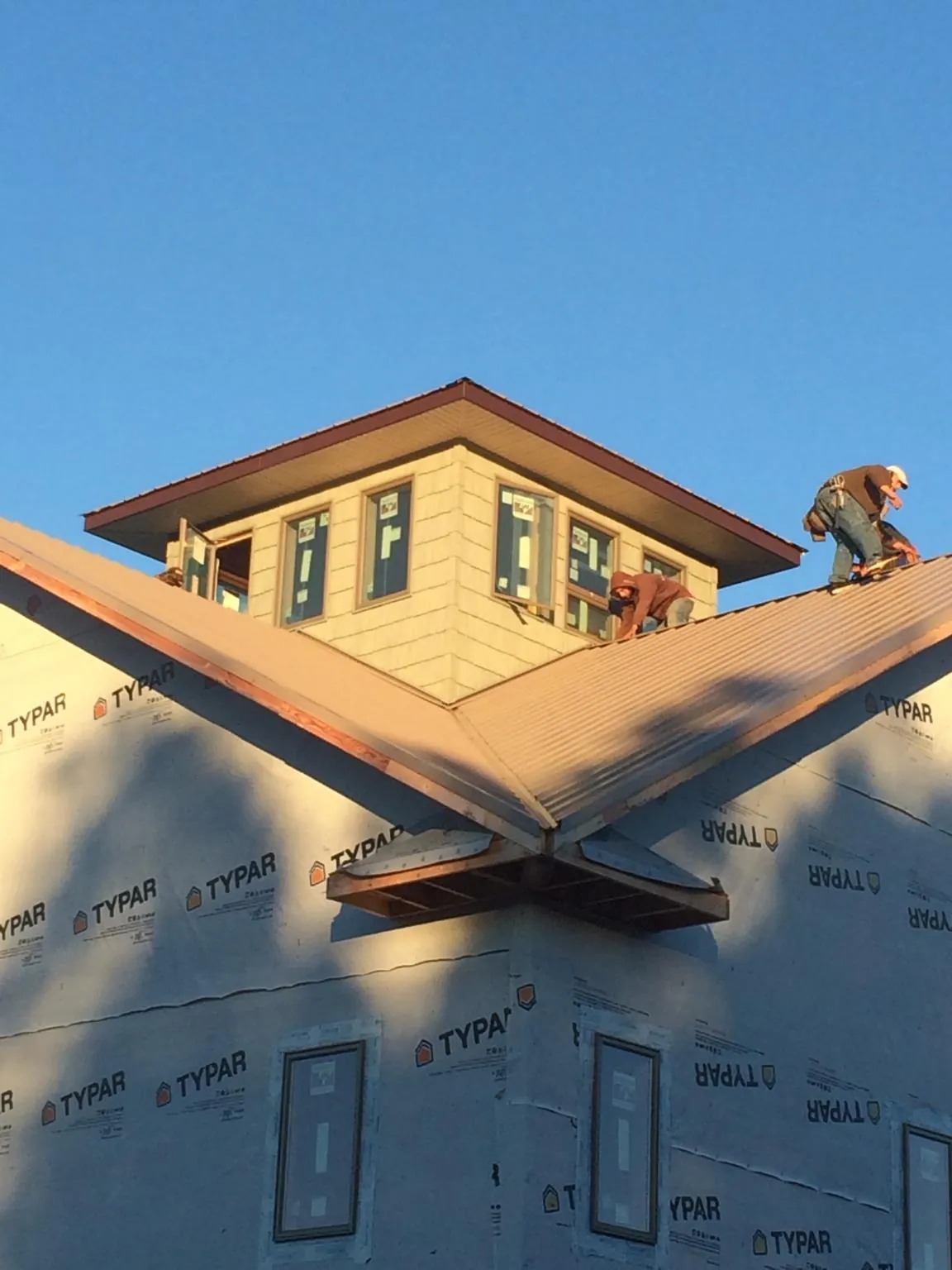 Roofers working around a rooftop cupola on a new metal roof at sunset — Roof Waterproofing in Five Points by Roofing Brothers